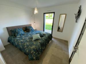 a bedroom with a bed with blue sheets and a mirror at 2 Maisons de vacances Sittelles Lodge in Concarneau