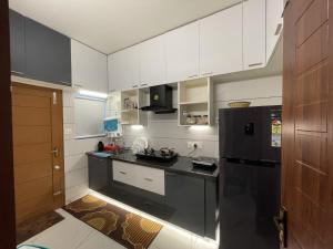 a kitchen with white cabinets and a black refrigerator at Diga Vista Lake View 4BHK Swimming Pool Cottage Munnar in Munnar