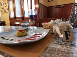 een bord eten op een tafel met een glas wijn bij Locanda del Santuario in Campiglia Cervo