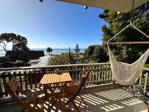 a patio with a hammock and a table and chairs at West End private apartment in Ohope Beach