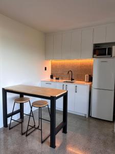 a kitchen with a wooden table and two stools at West End private apartment in Ohope Beach