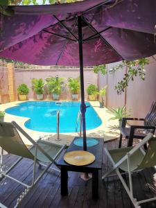 a table with an umbrella next to a swimming pool at L'Address Bar-Piscine-Restaurant in Cotonou