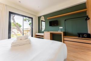 a bedroom with a large white bed with towels on it at Hotel Santanyi Port in Cala Figuera