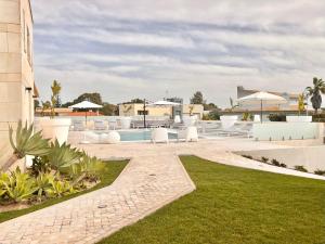 uma piscina num resort com mobiliário branco e relva em Soltroia Beach Court Villa em Tróia