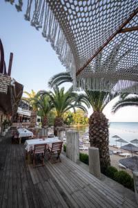 un patio al aire libre con mesas, palmeras y la playa en Sinop Antik Otel, en Sinope