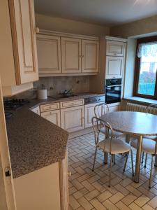 eine Küche mit weißen Schränken sowie einem Tisch und Stühlen in der Unterkunft Maison familiale au coeur des Vosges in Aumontzey