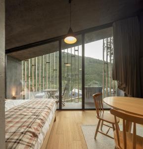 um quarto com uma cama, uma mesa e uma grande janela em Syntony Hotels - Paradinha Village em Arouca