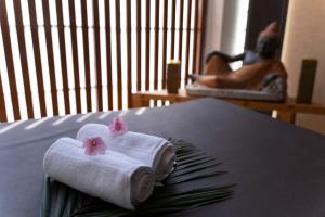 two towels with pink flowers on a bed at StayVista at The Yercaud Bungalow with Pvt Pool in Yercaud