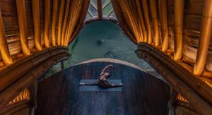 a woman is sitting on a mat in front of the water at Suenyo Eco Retreat in Tabanan