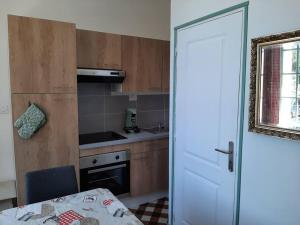 cocina con armarios de madera, mesa y puerta en Appartement le Vigeant, en Le Vigeant