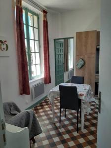 comedor con mesa, sillas y ventanas en Appartement le Vigeant, en Le Vigeant