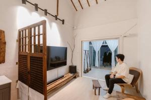 a man sitting in a chair in a living room with a tv at Spring Day in Jeonju