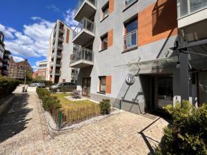 a building with a brick sidewalk next to a street at Platinum Jaglana Apartment - Wyspa Spichrzów in Gdańsk