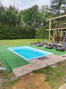a swimming pool with chairs and a green lawn at Apartament u Wioli in Okleśna