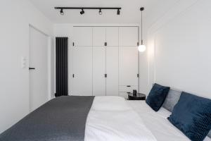 um quarto com uma grande cama branca com almofadas azuis em RentPlanet - Atal City Square em Breslávia
