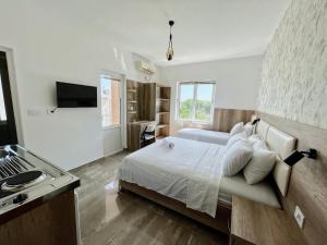 a white bedroom with a bed and a kitchen at Guest House Koliqi - Hotel & Apartments in Ulcinj