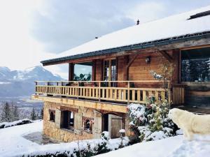 a log cabin with a deck in the snow at Le Cerf Enchanteur in Thyez
