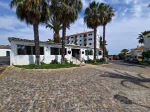 a white house with palm trees on a street at Tavira Cocooning T1 by YHA in Tavira