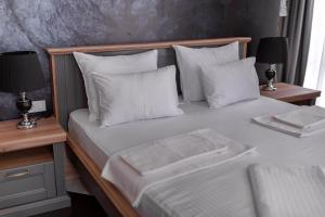 um quarto com uma cama com lençóis brancos e almofadas em Baba's Hotel & Spa em Dobra Voda