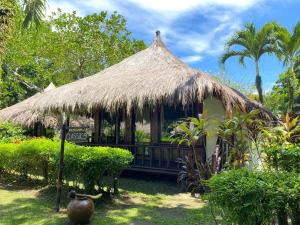 a hut with a thatched roof in a garden at Hijo Resorts Davao in Tagum