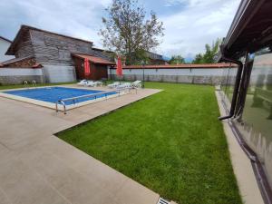a backyard with a swimming pool and green grass at Къща за гости - Вила Сидона in Banya