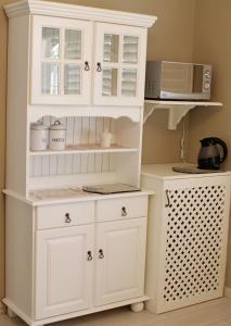 a white hutch with a microwave in a kitchen at Kastelein Guesthouse in Pongola
