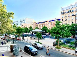 una persona montando un scooter por una concurrida calle de la ciudad en Deux pièces familial chic et confortable - Square Courteline - Nation - Paris centre en París