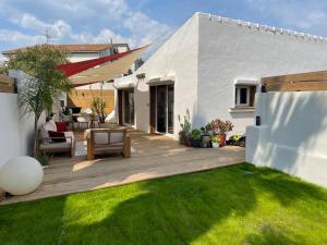 une arrière-cour avec une terrasse en bois et de l'herbe verte dans l'établissement Mini Villa Indépendante à 350m de la mer (LAX), à Lucciana
