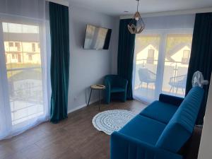 a living room with a blue couch and a large window at Wytworna Foczka in Sarbinowo