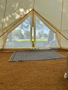une tente avec un tapis devant une fenêtre dans l'établissement RosaBell Bell Tent at Herigerbi Park, à Lincolnshire