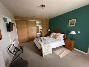 ein Schlafzimmer mit einem großen Bett und einer grünen Wand in der Unterkunft Ridge House Stables in Ashford