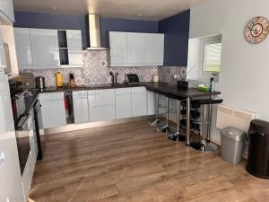 a kitchen with white cabinets and a wooden floor at Ridge House Stables in Ashford