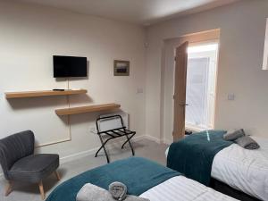ein Schlafzimmer mit 2 Betten, einem Stuhl und einem TV in der Unterkunft Ridge House Stables in Ashford