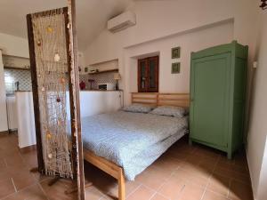 Il Casale Delle Farfalle في سيرولو: غرفة نوم مع سرير وكابينة خضراء
