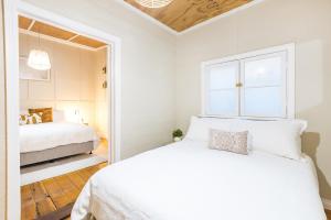a white bedroom with two beds and a mirror at Mellorie's on Lemon in Mildura