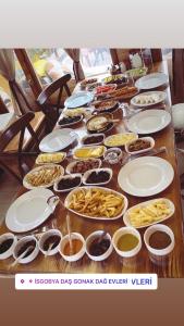 una larga mesa de madera cubierta con platos y tazones de comida en İSGOBYA DAŞ GONAK DAĞ EVLERİ, en Trabzon