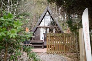 uma pequena casa com um portão de madeira e uma cerca em Wolf Lodge em Carrbridge