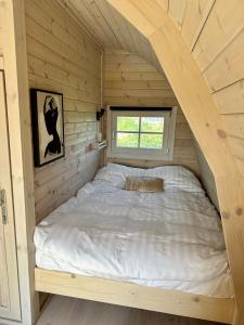 a bed in a log cabin with a window at LODGE, een super knus tiny house, nabij vaarwater en haven! in Belt-Schutsloot