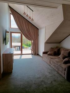 a living room with a couch and a large window at Apartamenty Polańczyk in Polańczyk