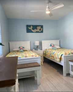 a bedroom with two beds and a table and a ceiling at Manasota Key Cottage B in Englewood