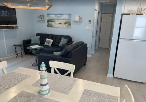 ein Wohnzimmer mit einem schwarzen Sofa und einem Kühlschrank in der Unterkunft Manasota Key Cottage B in Englewood