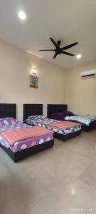 three beds in a room with a ceiling fan at Comfy room in Gunung Ledang 