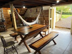 a wooden table and bench on a patio with a hammock at Casa dos Ingleses nos Canyons in Praia Grande