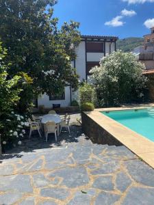 un patio con mesa y sillas junto a una piscina en Casa rural con piscina privada, en Casar de Palomero