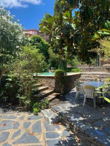 un patio con mesa, sillas y un árbol en Casa rural con piscina privada, en Casar de Palomero