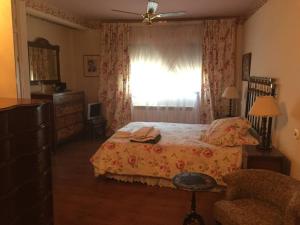 1 dormitorio con cama, ventana y silla en Casa rural con piscina privada, en Casar de Palomero