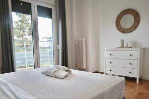 a white bedroom with a bed and a window at SynPiraeus Apartments & Studios in Piraeus
