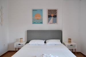 um quarto com uma cama e duas mesas de cabeceira brancas em SynPiraeus Apartments & Studios em Piraeus