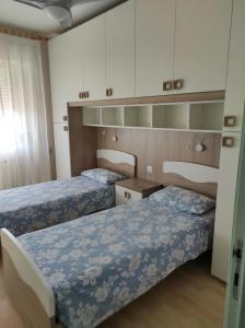 2 łóżka w małym pokoju z białymi szafkami w obiekcie Attico solare fronte mare w mieście Porto Recanati