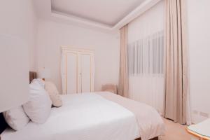 a white bedroom with a white bed with white pillows at Giorgio Boutique Hotel in Sliema